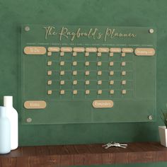 a green wall with a calendar on it next to a white vase and some scissors