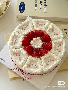 a cake with strawberries on it sitting on top of a table next to some books