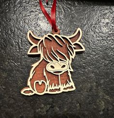 a wooden ornament shaped like a cow with a red ribbon hanging from it's neck