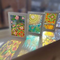 four cards are sitting on top of a table with flowers and leaves painted on them