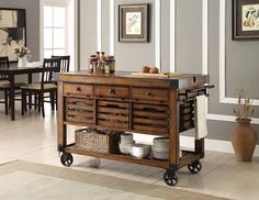 a kitchen island with drawers and baskets on it's wheels in a dining room