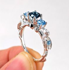 someone is holding a ring with blue and white stones