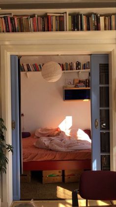 an open door leading to a bedroom with a bed and bookshelf in it