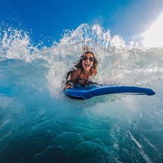 a woman riding on top of a blue surfboard in the middle of the ocean