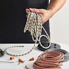 a person is holding some colorful cords on a table with other items around it and the cord has been pulled out