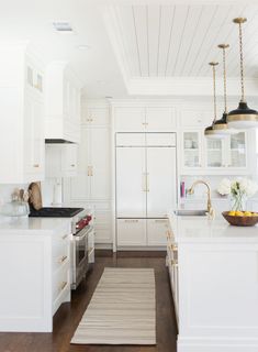 a large kitchen with white cabinets and wood flooring, along with an area rug on the floor