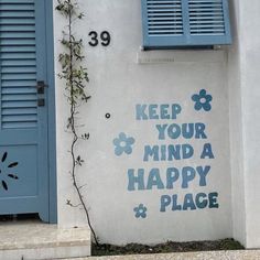 a white building with blue shutters on the side and a sign that says keep your mind a happy place