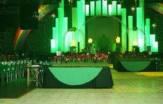 a stage set up for a party with green lighting and flowers in the center area