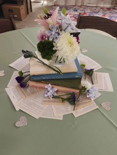 a vase filled with flowers sitting on top of a table covered in books and paper