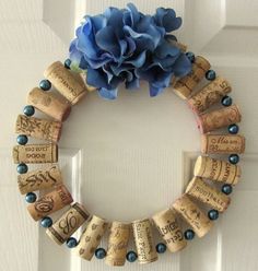 a wreath made out of wine corks with a blue flower on the front door