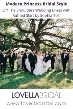 the bridal party is posing for a photo in front of a large oak tree