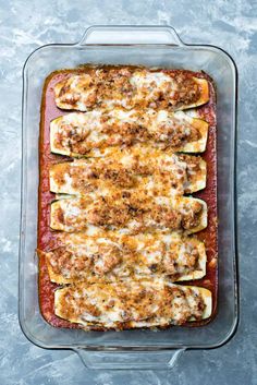 a casserole dish with meat, cheese and sauce in it on a blue surface