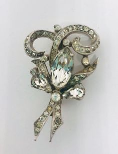 Exquisite vintage rhinestone bow brooch. Rhodium plated metal in a ornate scrolling design and pave set rhinestones brooch. Large center rhinestone. Wonderfully detailed.... including rhinestone set upturned leaves. Absolutely gorgeous!! In excellent vintage condition with minimal age appropriate wear. All stones securely prong and pave set. Roll over clasp secure. Measures 1 5/8 inches tall by just over 1 inch wide. Beautiful!! Vintage Rhinestone Brooches For Vintage Events, Silver Jeweled Brooches For Formal Occasions, Formal Silver Jeweled Brooches, Antique Rhinestones Brooch For Vintage Events, Antique Rhinestone Brooches For Vintage Events, Vintage Rhinestone Brooches For Anniversary, Vintage Brooches With Sparkling Stones As Gift, Vintage Brooches With Sparkling Stones For Gift, Vintage Anniversary Brooch With Sparkling Stones