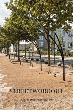 an empty park with benches and trees in the background that reads, streetworkout