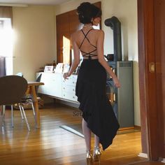 a woman in a black dress is walking through the room with her back to the camera