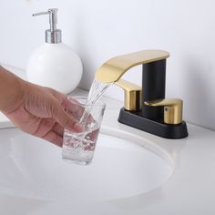 a person's hand is pouring water into a glass from a faucet