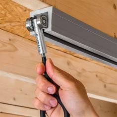 a person is holding a wrench in front of an air conditioner on the ceiling