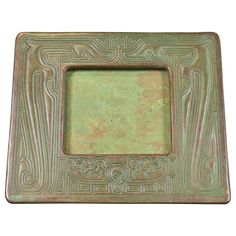 a square metal frame with an intricate design on it's sides, and a green background