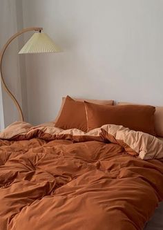 a bed with an orange comforter and pillows