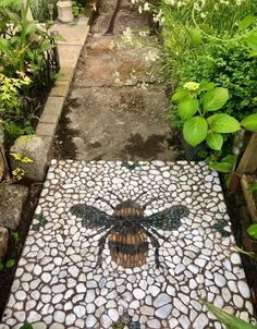 a mosaic tile floor with a bee painted on it in the middle of a garden