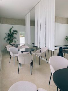 an empty room with white chairs and black tables