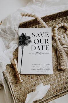 save the date cards on a wicker tray with tassels and white flowers