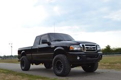 a black pickup truck parked on the side of a road in front of a field