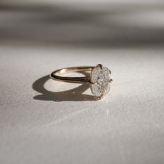 a diamond ring sitting on top of a white surface with sunlight coming through the window