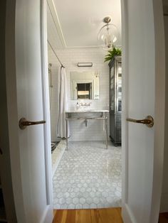 an open door leading to a bathroom with a sink and mirror