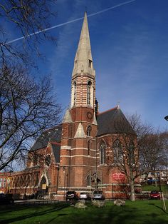 an old church with a steeple and clock tower in the middle of a grassy area