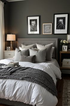 a bedroom with gray walls, white bedding and pictures on the wall above it