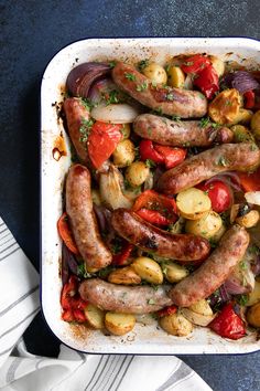 a casserole dish with sausages, potatoes and tomatoes