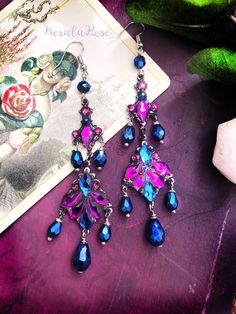 This pair of Handmade Chandelier Earrings is made with rich Metallic Blue crystal teardrops hanging from rhinestone-decorated brass pendants.  The Aurora glass stones add a mystical sparkle!  They are antiqued to have a beautiful vintage appeal.  Pierced with french wires (as shown), leverbacks, clip-ons or posts, just select from the pull-down menu. -4 " Long (includes piercing) x 1" Wide -0.2 oz. ea. Metal Finishes Available: -Silver (as pictured) -Bronze *These can be shortened up by removing Jeweled Dangle Chandelier Earrings, Nickel-free Long Drop Chandelier Earrings For Party, Nickel Free Long Drop Chandelier Earrings For Party, Bohemian Teardrop Chandelier Earrings For Party, Bohemian Jeweled Dangle Chandelier Earrings, Pink Teardrop Chandelier Earrings, Nickel Free, Bohemian Crystal Chandelier Drop Earrings, Bohemian Crystal Chandelier Earrings, Mystical Goddess