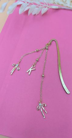 a pair of scissors on a pink surface next to some flowers and a chain necklace