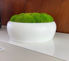 a white bowl filled with green moss sitting on top of a counter next to a microwave