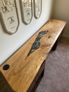 a wooden bench sitting in the middle of a room next to two wall hangings