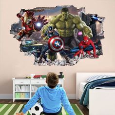 a boy sitting on the floor in front of a wall mural with avengers and spider - man