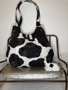 Shoulder Bag - Cow Print Lovely quilt-weight cotton shoulder bag is featured in a black and white cow print.  Looking inside is one large pocket with plenty of additional storage.  Top secures with a loop and toggle button.  This item is 100% washable (all pre-washed) and warm iron. Measurements: 10-1/2" H x 13" W Double handles are about 20" Black Bag With Cow Print For Everyday Use, Casual Everyday Bag With Cow Print, Casual Cow Print Bags For Daily Use, Black And White Cow Print, White Cow Print, Black And White Cow, Toggle Button, White Cow, Cow Print