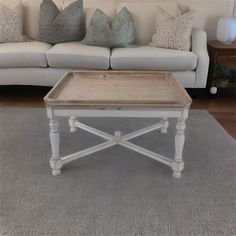 a coffee table sitting on top of a gray rug in front of a white couch