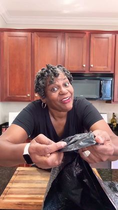 a woman is sitting at the kitchen counter with her hands in a bag and smiling