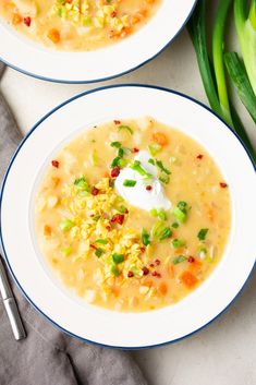 two white bowls filled with soup next to green onions