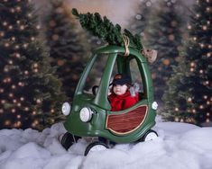 a baby in a green car with a christmas tree on top