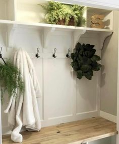 a white coat rack with plants and towels on it, next to a wooden bench