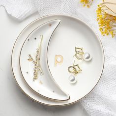 two white plates with gold and pearl jewelry on them