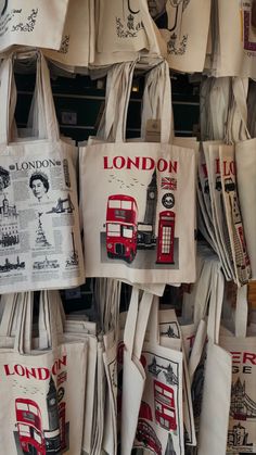 tote bags with london images on them are hanging up in a shop window display