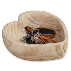 a wooden bowl with scissors and other items in it on a white background, there is also a pair of scissors