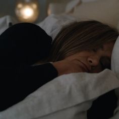 a woman is laying in bed with her head on the pillow and looking at the camera