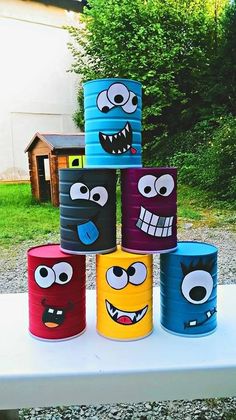 some paper cups with faces painted on them sitting on top of a table in front of trees