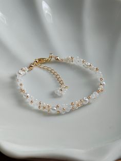 a bracelet with pearls and gold beads on a white plate