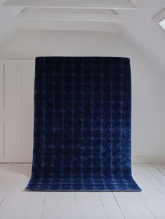 a blue blanket sitting on top of a wooden floor next to a white wall and ceiling